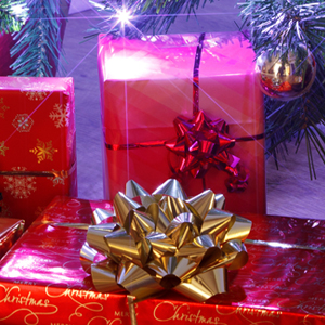 Bottom of a lit up Christmas Tree with many red and yellow wrapped presents