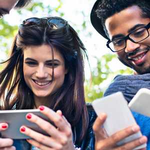 Group of friends huddled together checking their phones